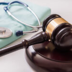 Scrubs, stethoscope, and a gavel, signifying medical malpractice.