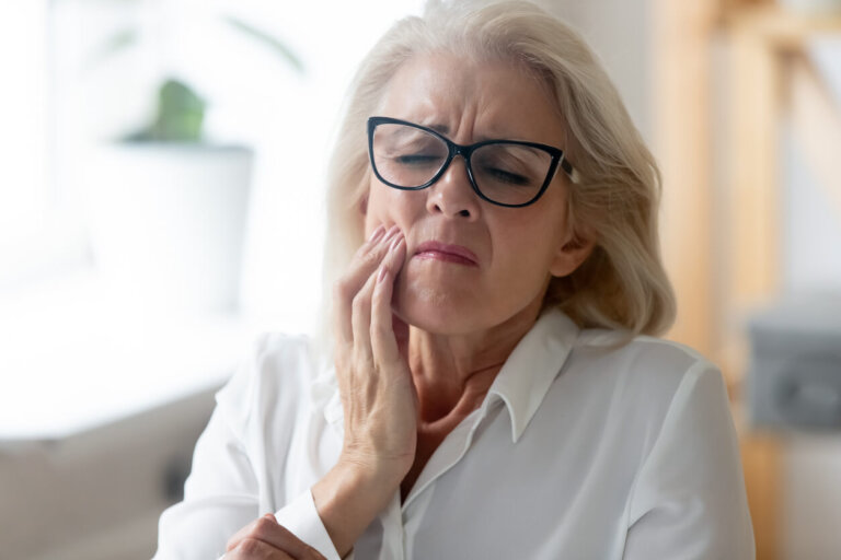 middle aged woman holding mouth in pain