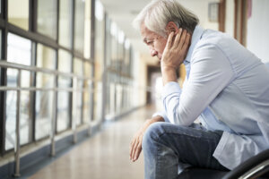 senior asian patient sitting in hospital hallway looking sad and depressed
